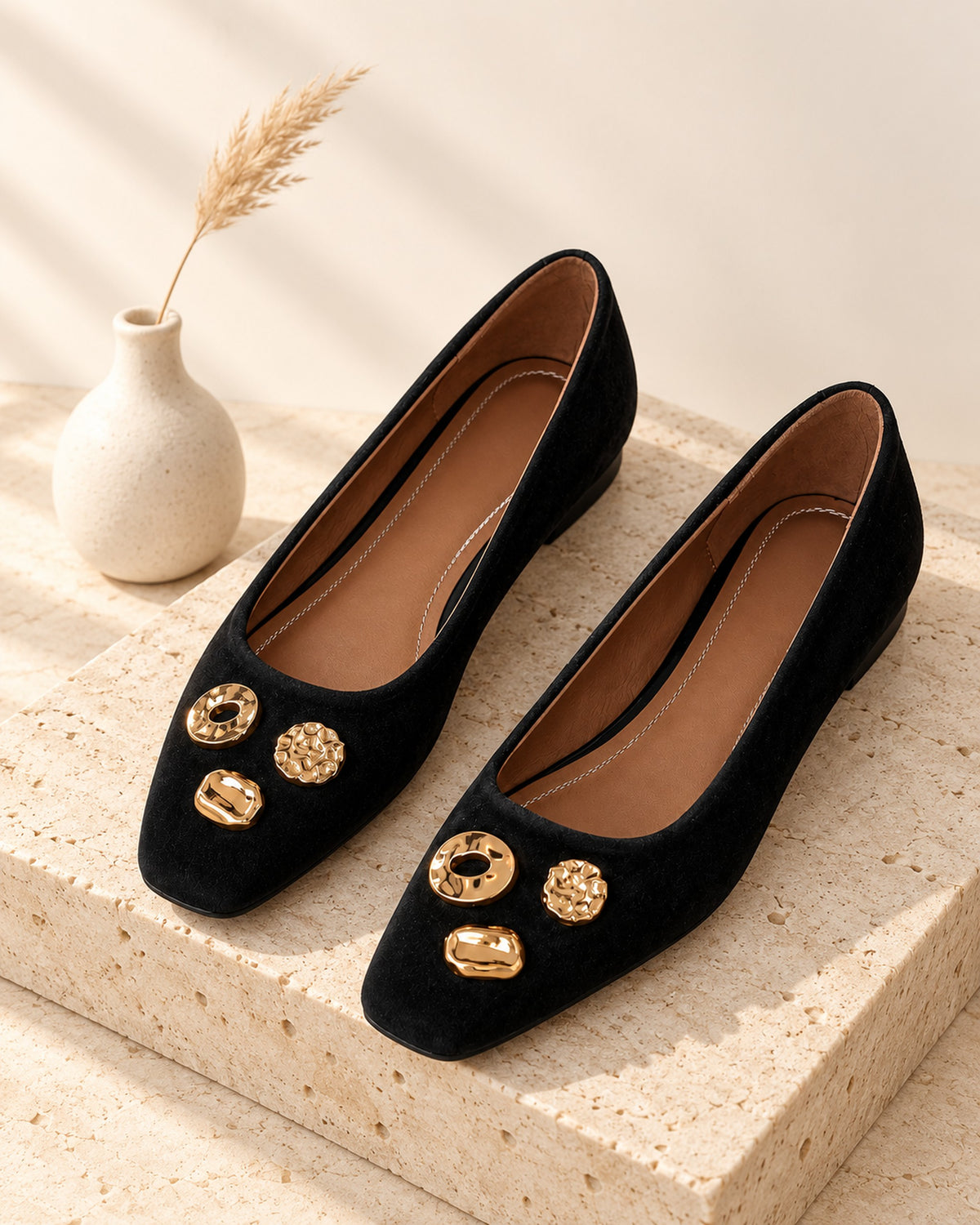 Apolline suede square-toe flat with gold-tone ornaments in Black, still life on travertine