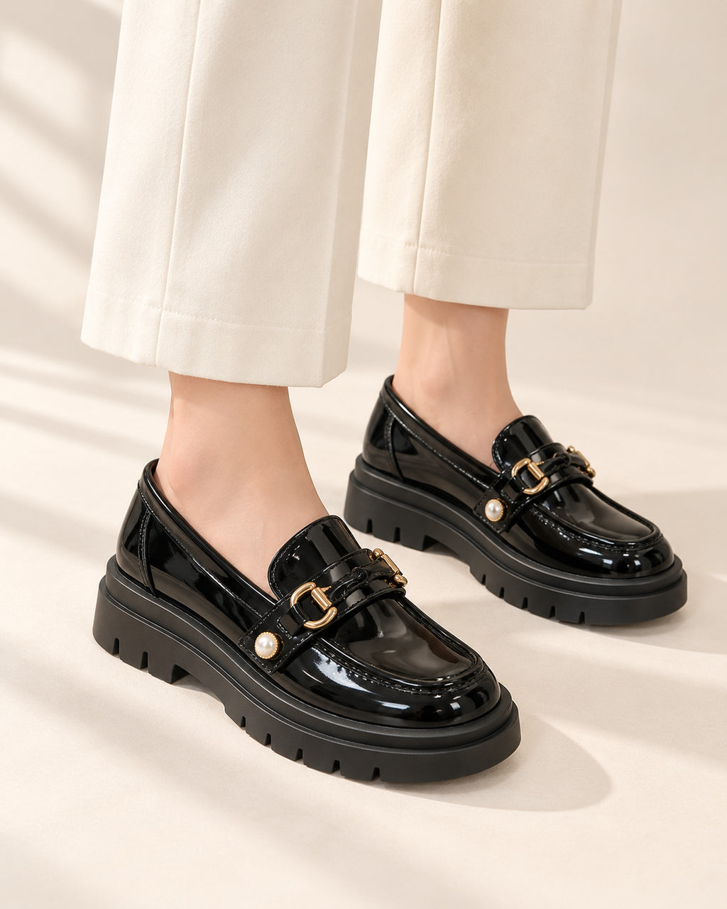 Bérénice patent-finish platform loafer with horsebit buckle in Black, worn