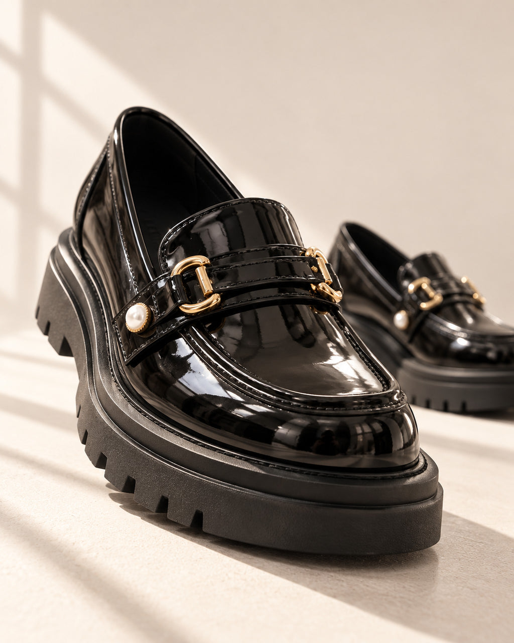 Bérénice patent-finish platform loafer with horsebit buckle in Black, editorial low-angle view