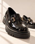 Bérénice patent-finish platform loafer with horsebit buckle in Black, editorial low-angle view