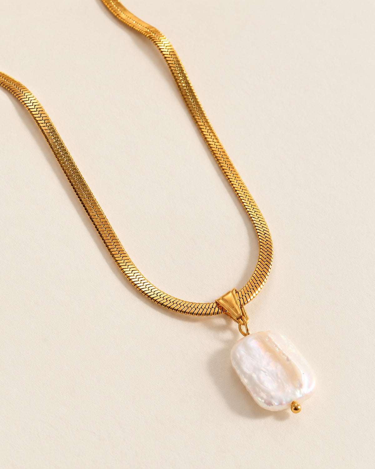 Celeste gold-tone herringbone chain necklace with baroque pearl drop, three-quarter view