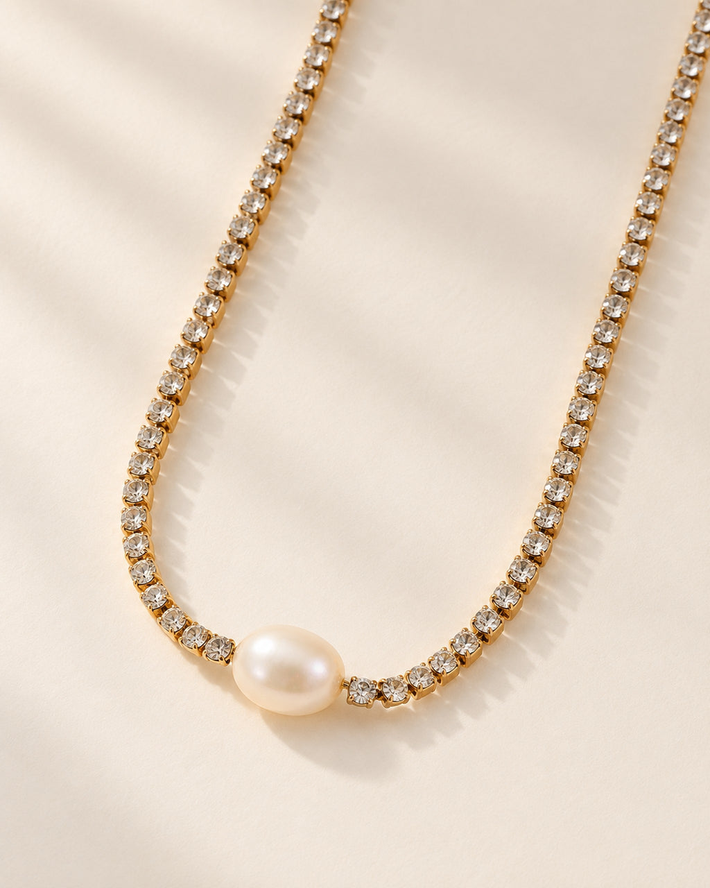 Celeste gold-tone crystal tennis chain necklace with oval pearl, three-quarter view