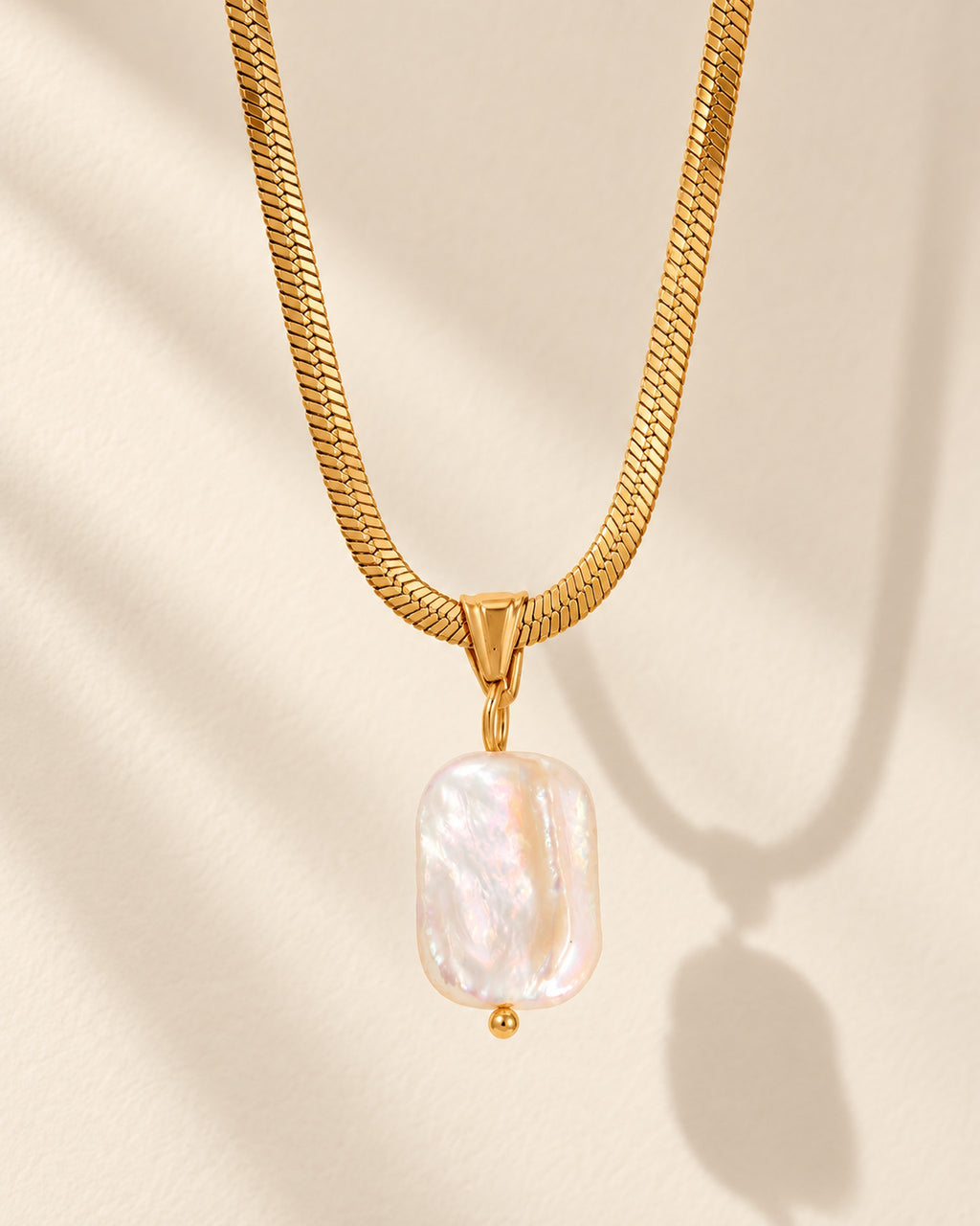 Celeste gold-tone herringbone chain necklace with baroque pearl drop, editorial view
