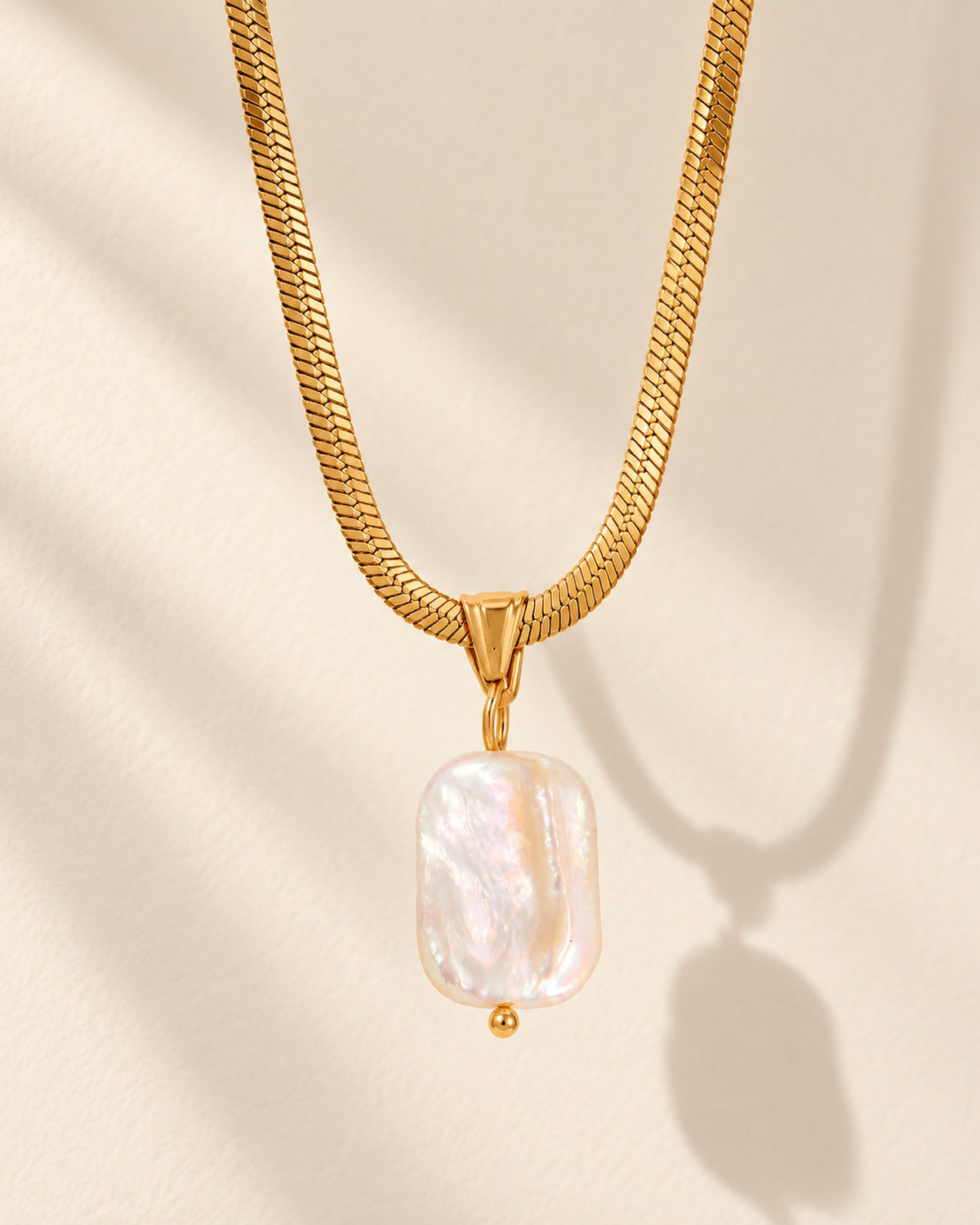 Celeste gold-tone herringbone chain necklace with baroque pearl drop, editorial view
