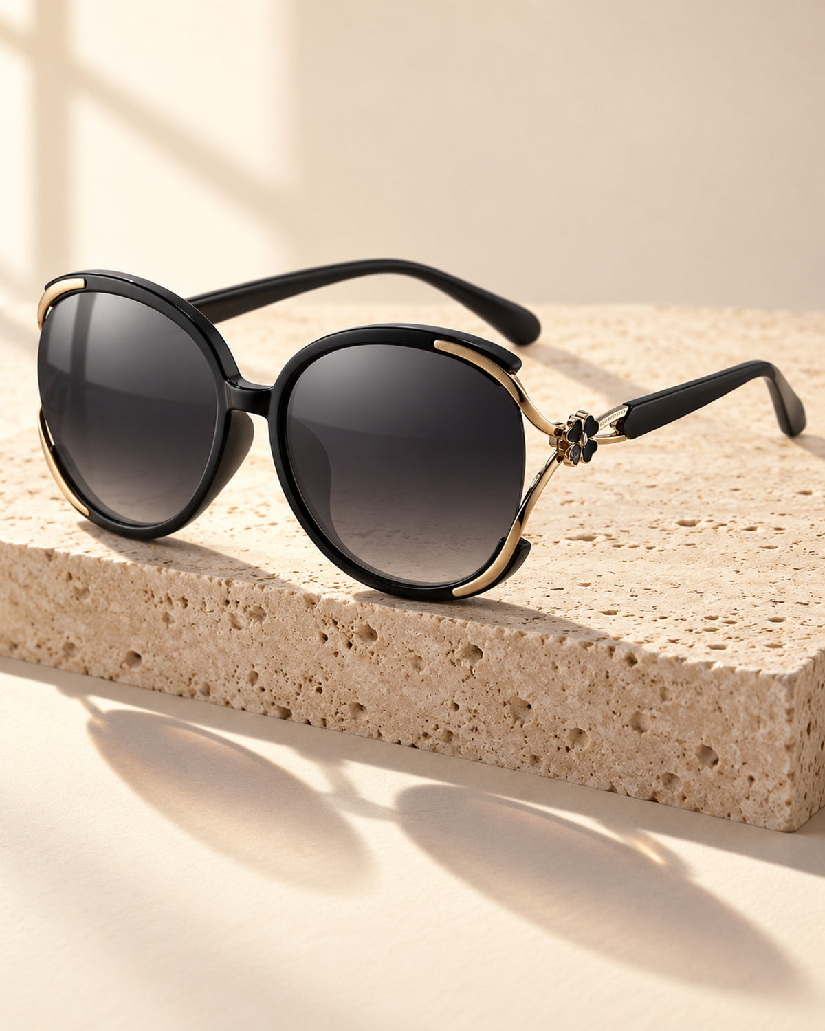 Chiara cat-eye sunglasses in black frame, gray gradient lenses, still life on travertine