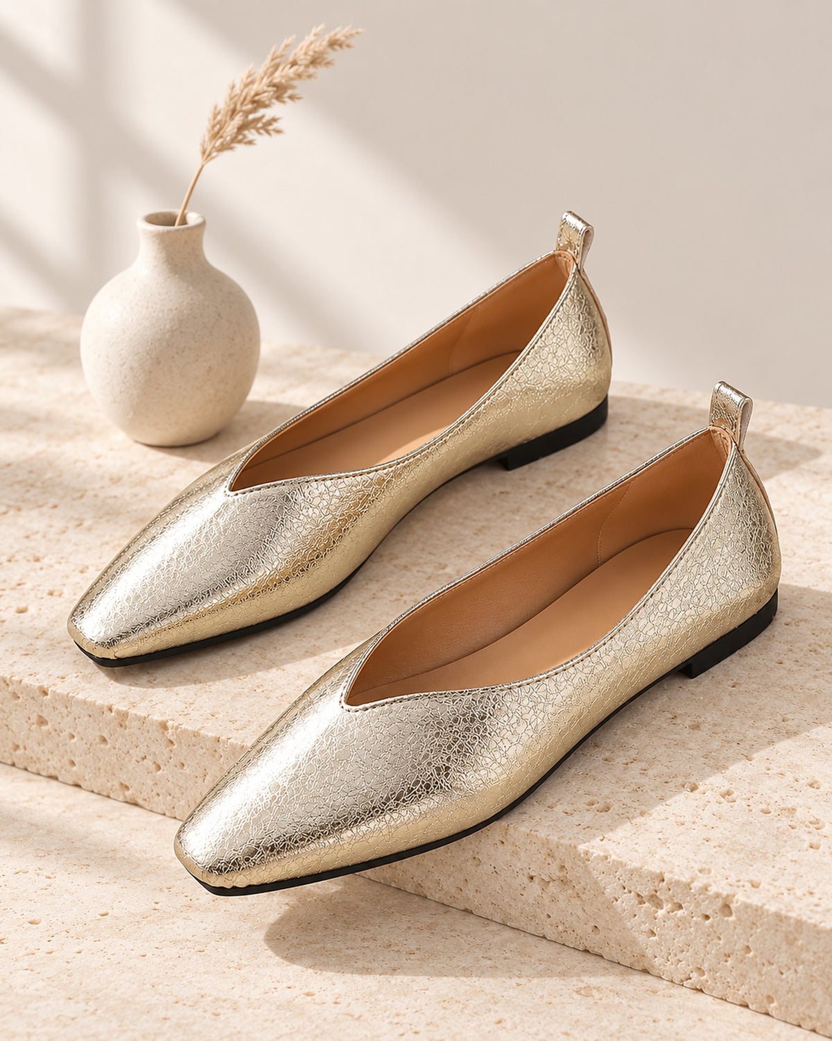 Sélène metallic crinkle-finish V-cut ballet flat in Gold, still life on travertine