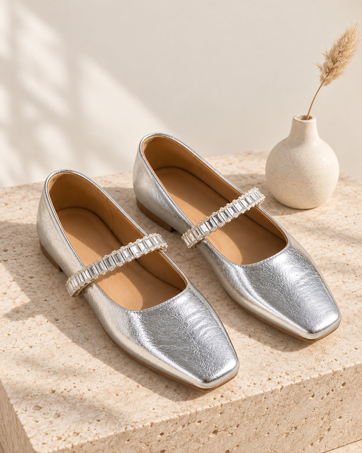 Noémie square-toe metallic ballet flat with rhinestone strap in Silver, still life on travertine